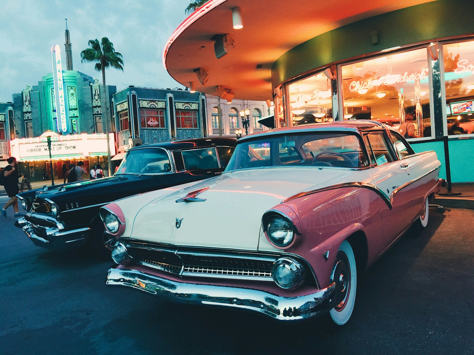 classic cars white and pink coupe parked beside black car